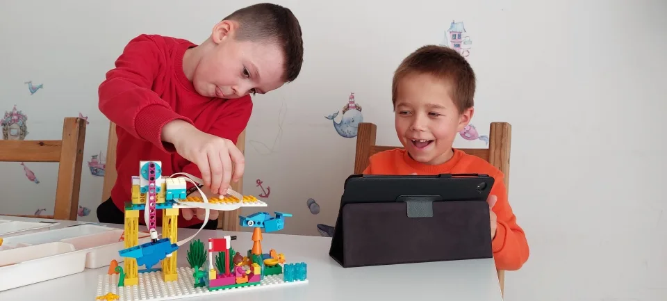 Dwójka dzieci buduje robota z klocków LEGO na warsztatach FA-BRYKA